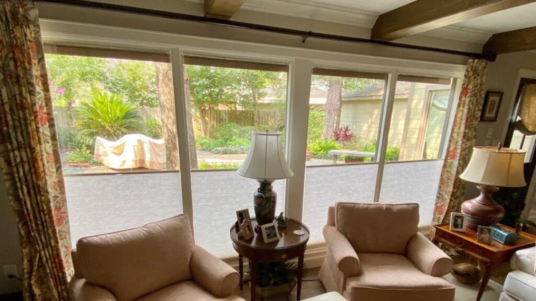 A living room with two chairs, a table, lamps and a large window