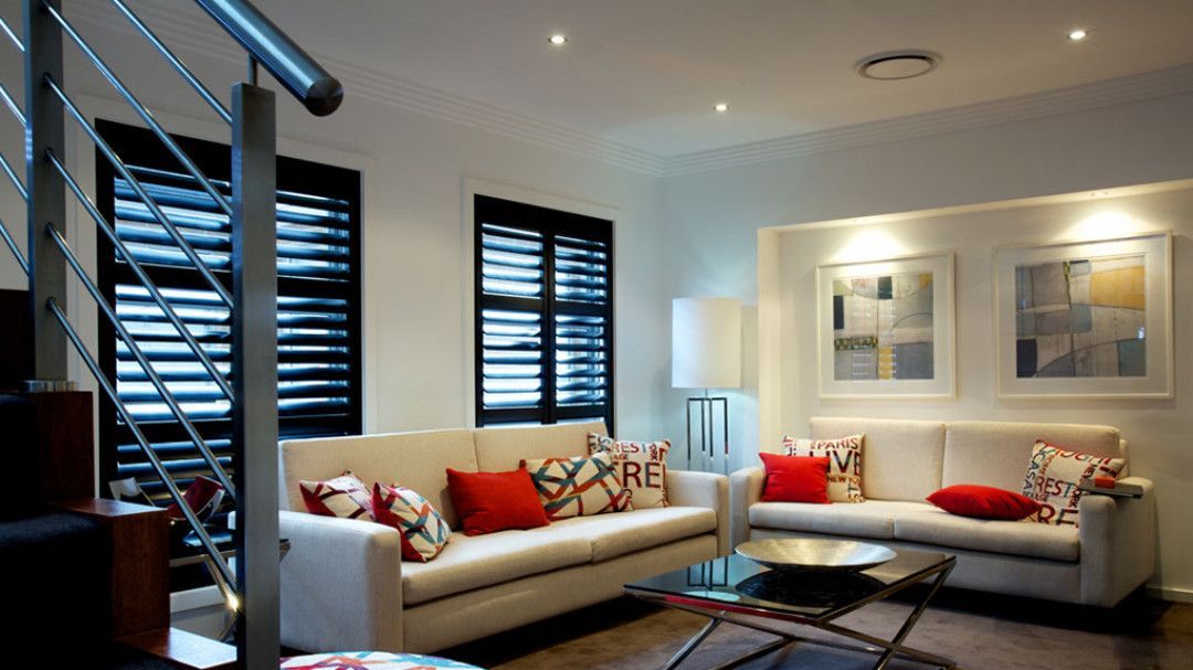 A living room with a white couch and red pillows