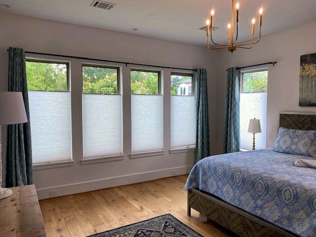 A bedroom with a bed, a lamp, and a chandelier 