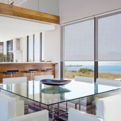 A dining room with a glass table and white chairs