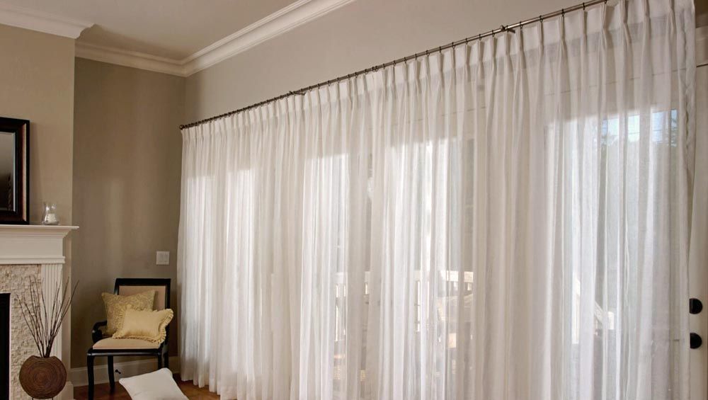 A living room with white curtains and a fireplace 