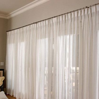 A living room with a lot of white curtains on the windows
