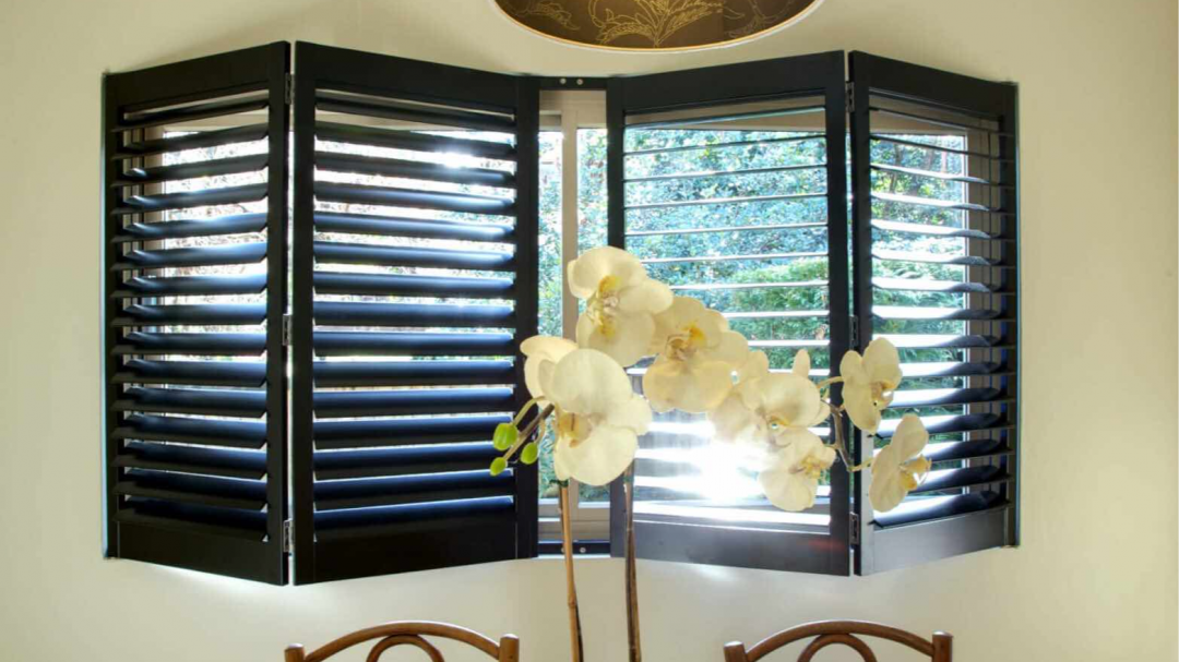 A window with shutters and flowers in front of it