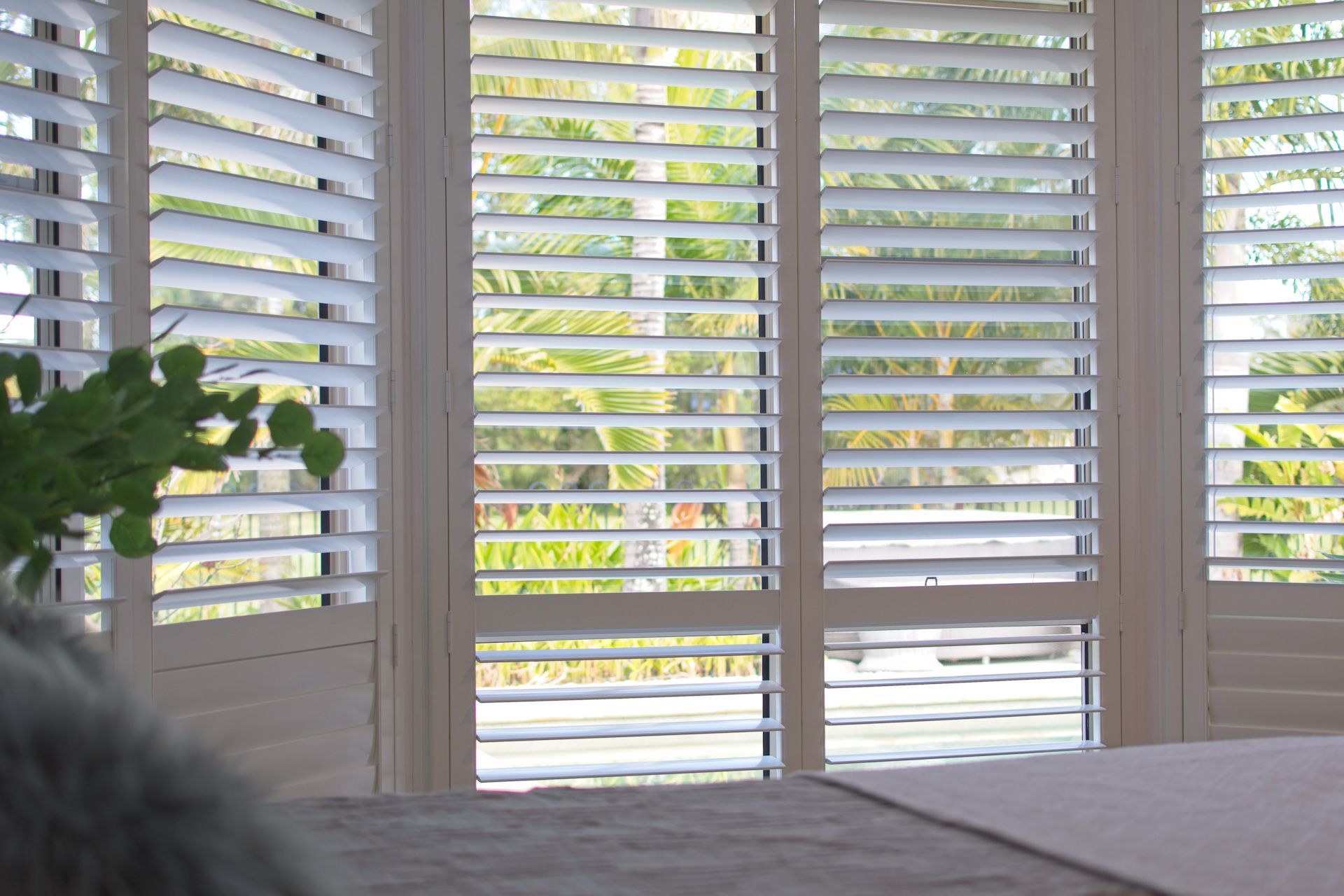 A bedroom with a bed and shutters on the windows
