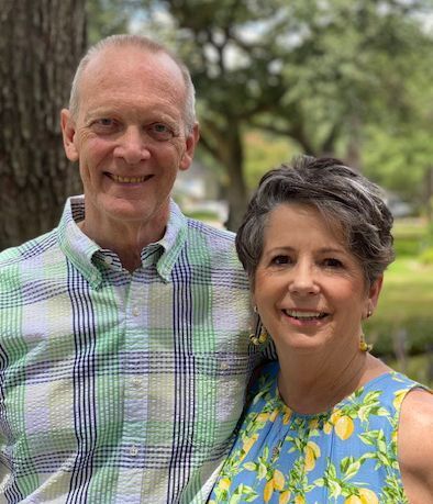 A man and a woman are posing for a picture in front of a tree