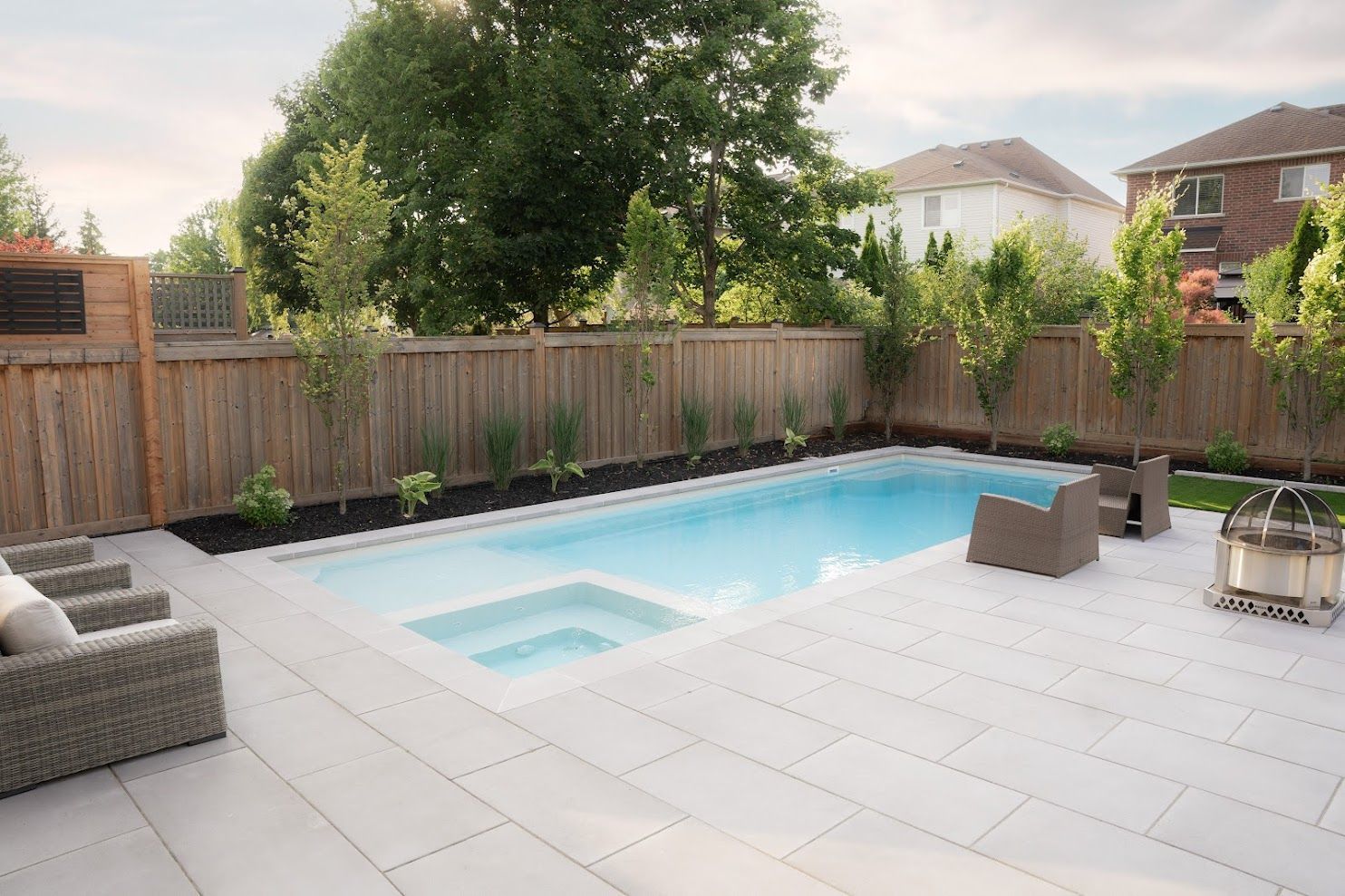 Modern backyard with a Latham Astoria 14 fiberglass pool, built-in spa, stone patio, lounge seating 