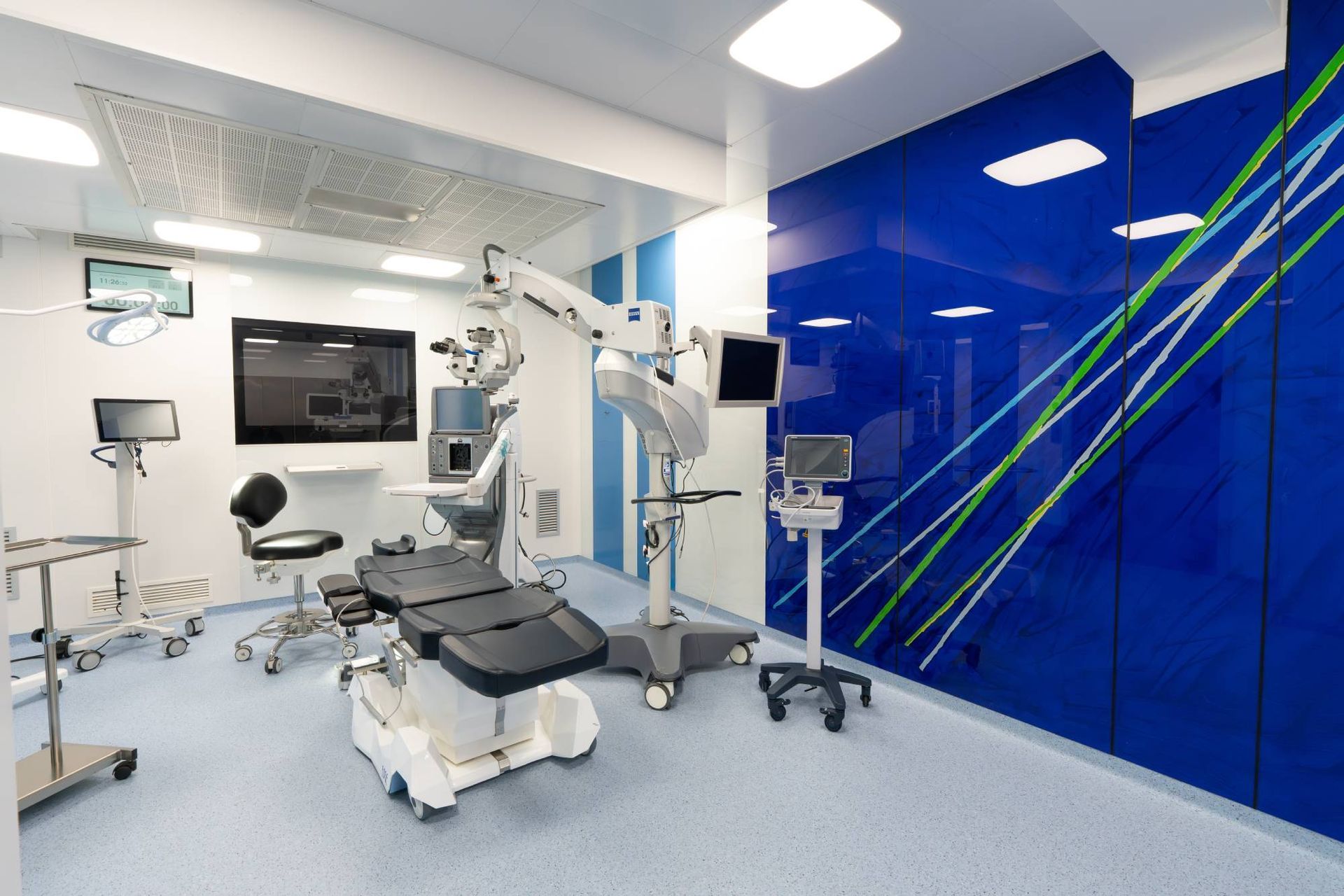 Sala operatoria moderna con robot chirurgico, monitor e armadietti blu per la conservazione.