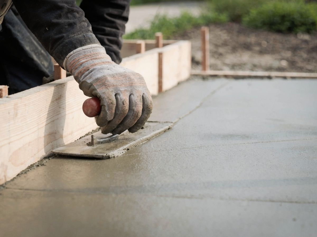 Worker smoothing wet concrete with a trowel at a construction site