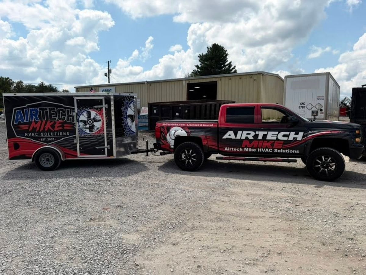 Red and black AIRTech truck towing a matching trailer in a gravel lot under a cloudy sky