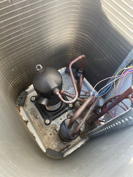 Close-up of a metal compartment with a black pump or valve assembly and colored wires inside.
