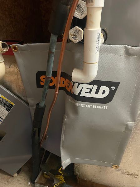 Gray SOUDAL-branded heat blanket around pipes and wires in an industrial workspace