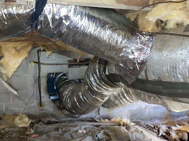 Silver HVAC ducts in a damaged ceiling with exposed insulation and wiring