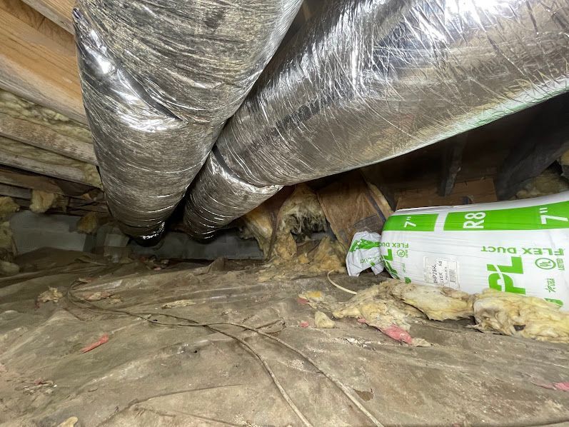 Insulated crawl space with ductwork and a white-green pipe on the right