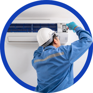 Technician in blue uniform inspecting a wall-mounted air conditioner with a smartphone