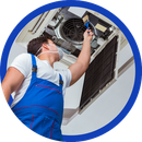 Technician in blue overalls servicing an air conditioner unit overhead
