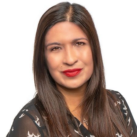Portrait of a woman with long dark hair, red lipstick, and a black patterned top on a white background