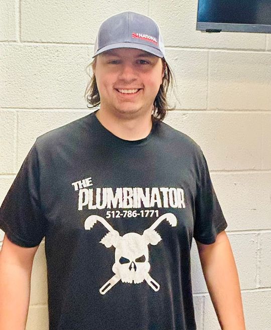 Person in a lime green T-shirt and cap standing against a corrugated metal wall.