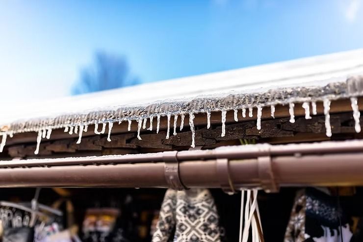 Icicles hanging from a roof edge above a market stall with hanging textiles