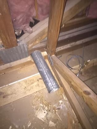 Damaged attic floor with exposed insulation and a loose silver duct pipe between wooden joists