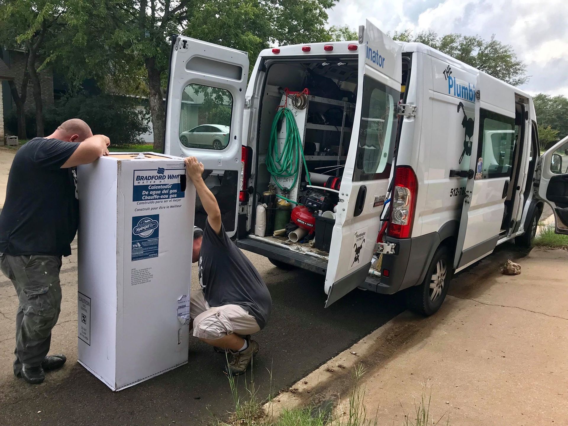 Workers unload a white service van with open rear doors on a roadside.