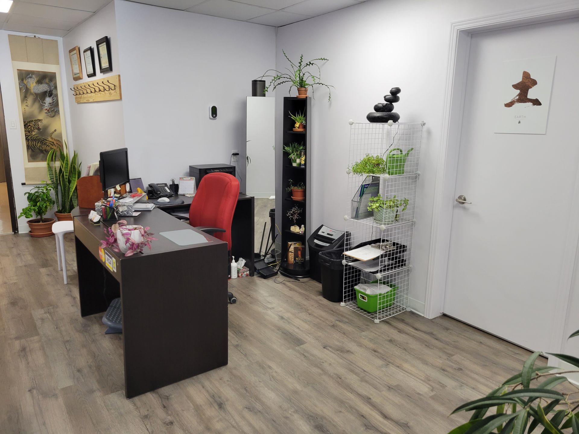 Bureau moderne avec bureau, chaise rouge, plantes et portes blanches sur parquet gris