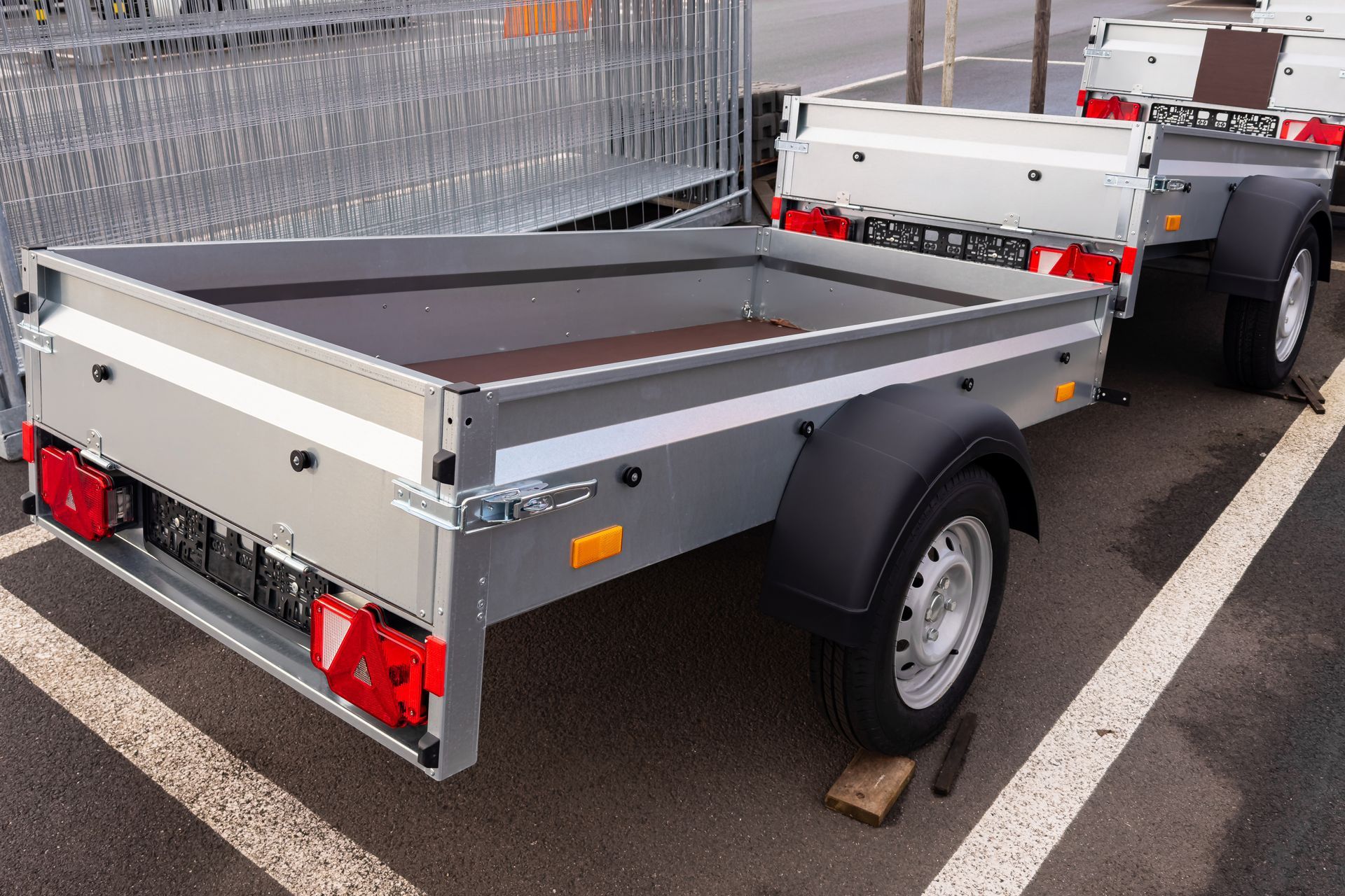 Compact metal utility trailer parked in a lot.
