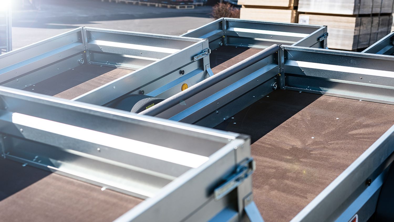Open utility trailers lined up outdoors, showing metal frames and flat beds ready for hauling.