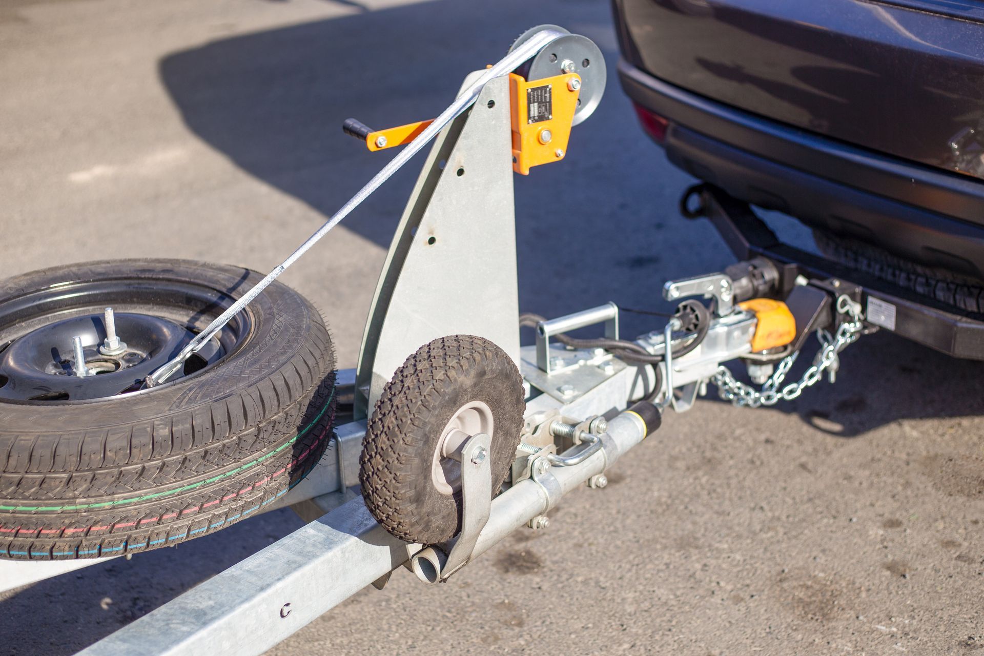 A close-up of a car towing a trailer on a road.