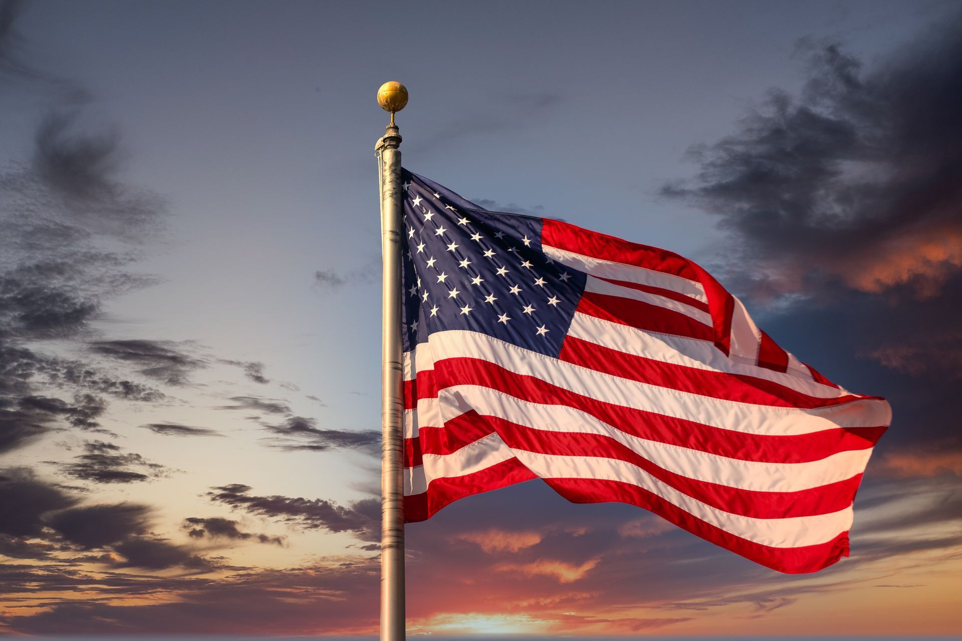 An American flag on flagpole waving in the wind. An American flag on flagpole waving in the wind.
