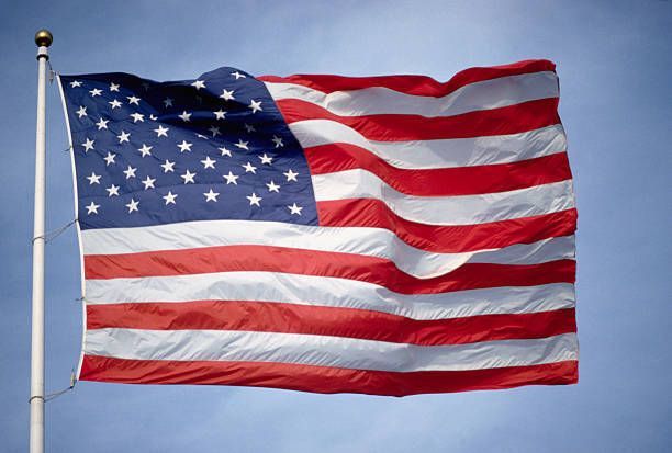 American flag waving on a flagpole against a blue sky, highlighting quality flagpoles in Westborough