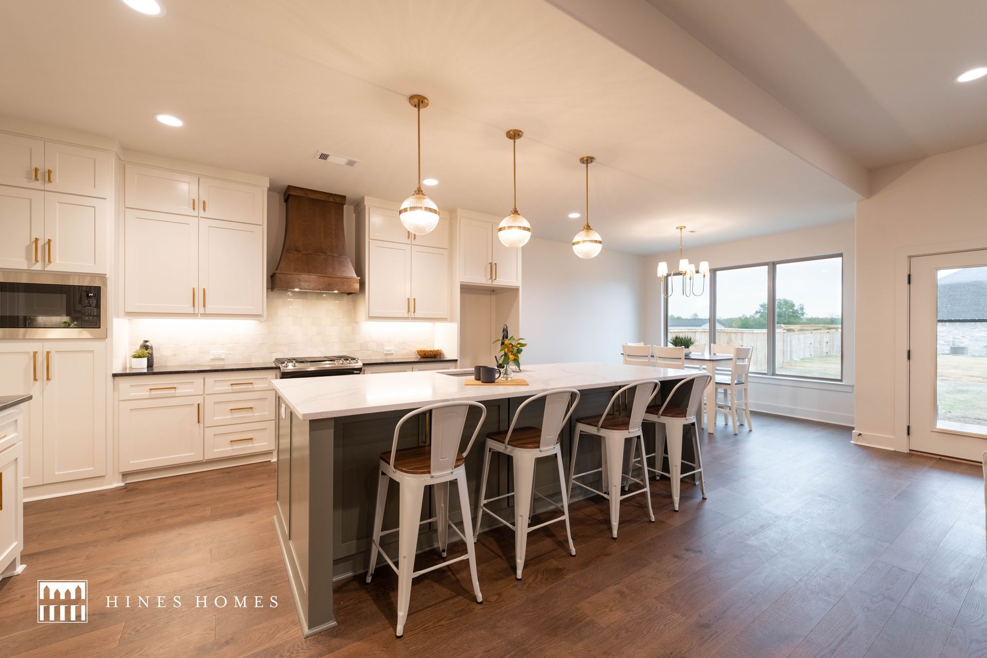 open floor plan kitchen view of the island with tall seats and white cabinets built by hines homes