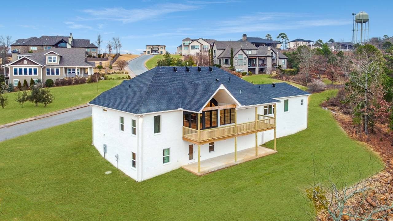 The back of a modern new constructed home with a double deck and white exterior. Big back yard with a view
