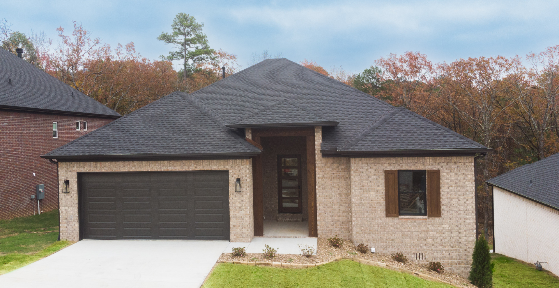 brand new construction home with brown garage door and beige brick
