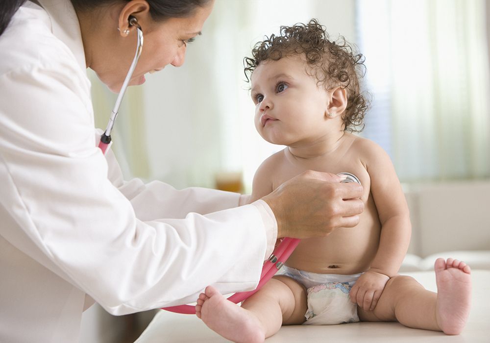 Un medico sta esaminando un neonato con uno stetoscopio.