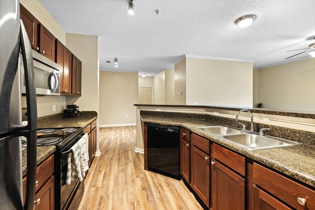 Kitchen area with granite countertops, stainless steel appliances, and dark wood cabinets.