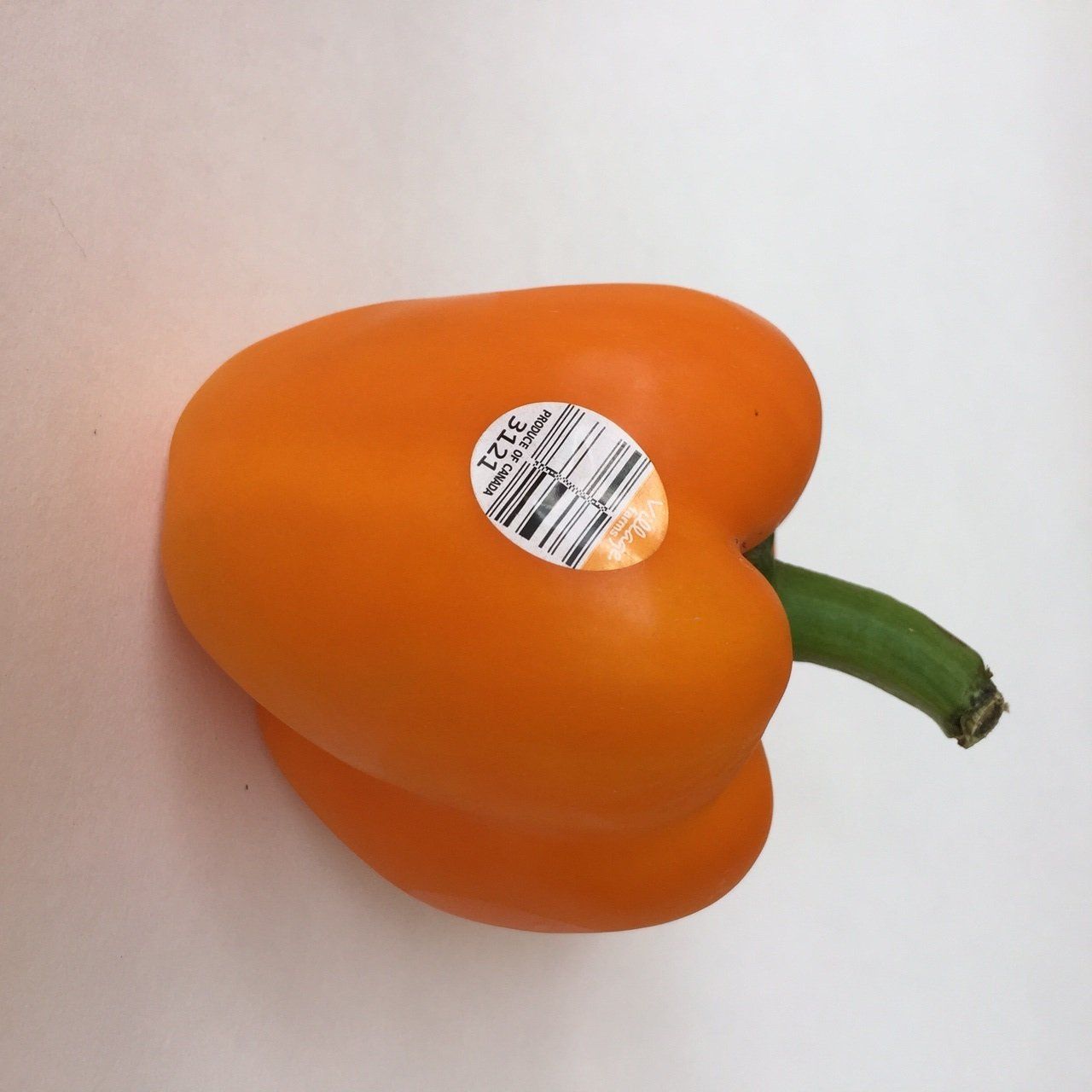An orange pepper with a sticker that says 1235 on it