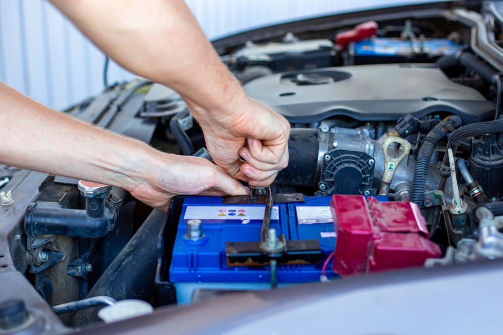 A Man Is Fixing A Car Battery With A Wrench — Valley Brake & Clutch In McDougalls Hill, NSW