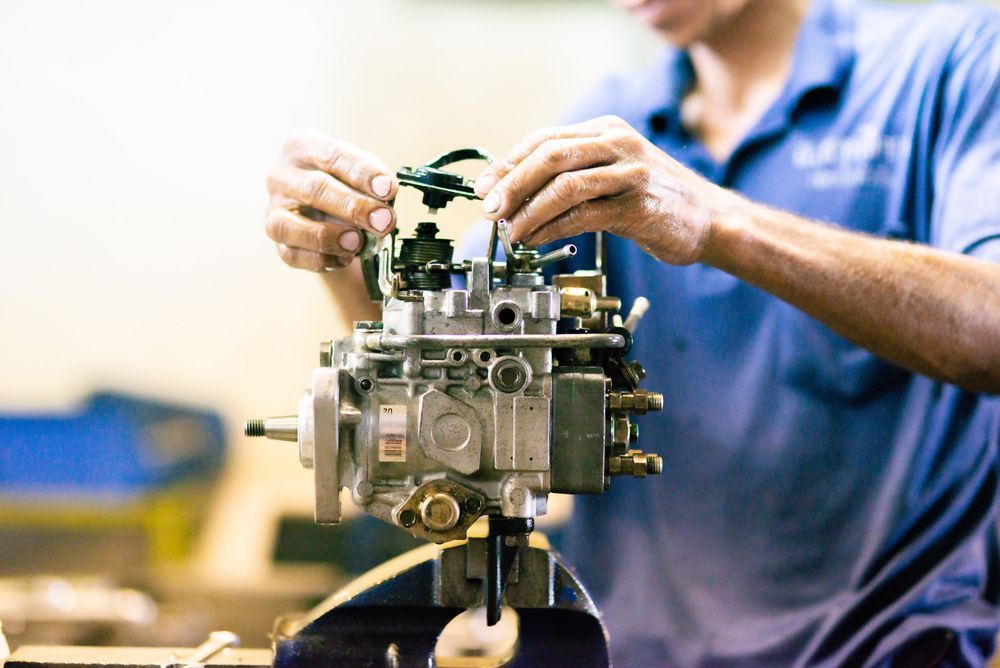 A Man In A Blue Shirt Is Working On A Machine — Valley Brake & Clutch In McDougalls Hill, NSW