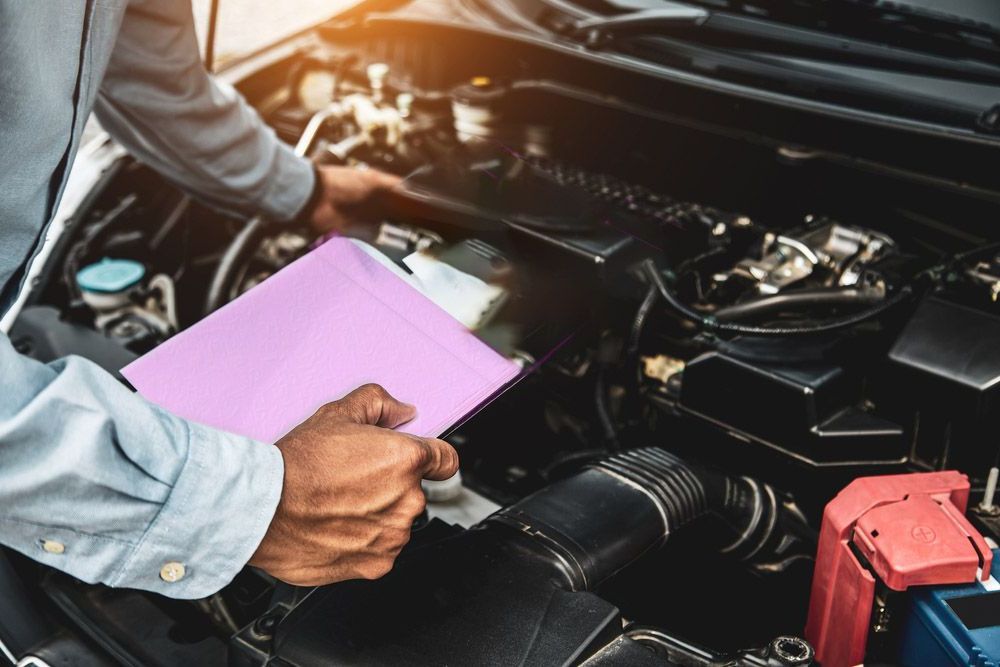 A Man Is Looking Under The Hood Of A Car While Holding A Clipboard — Valley Brake & Clutch In McDougalls Hill, NSW