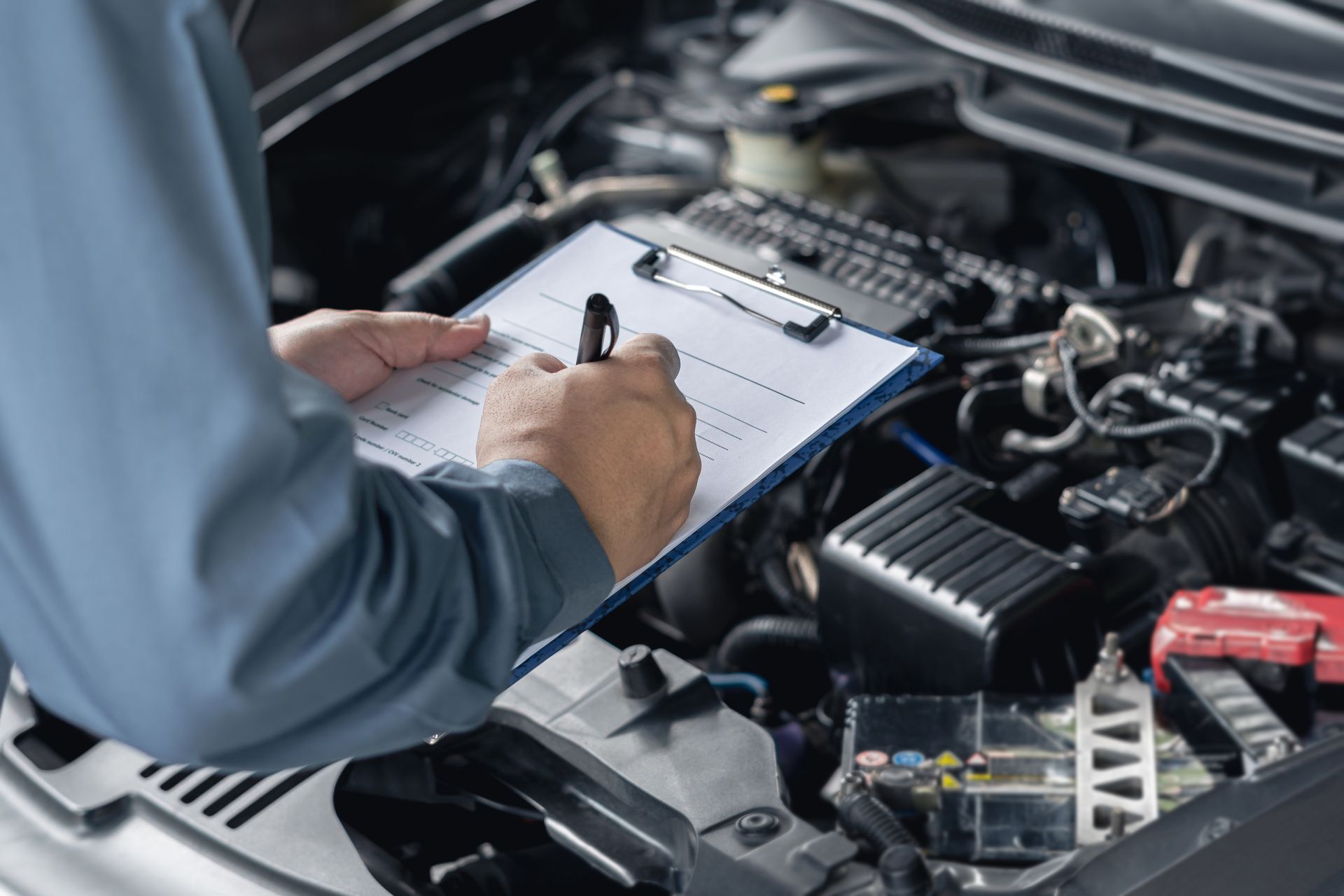 A Mechanic Is Writing On A Clipboard Under The Hood Of A Car — Valley Brake & Clutch In McDougalls Hill, NSW