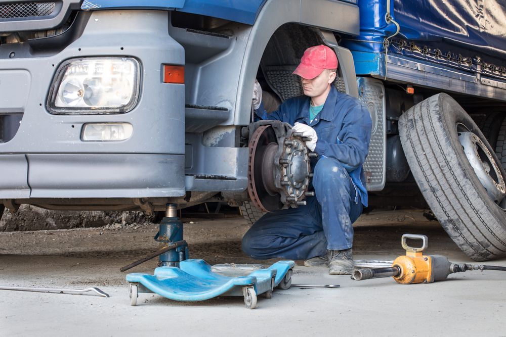 A Man Is Working On A Truck In A Garage — Valley Brake & Clutch In McDougalls Hill, NSW