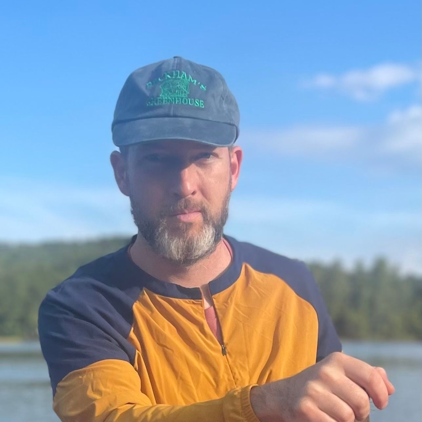 Man in blue cap and yellow/navy shirt, outdoors, looking at the camera.