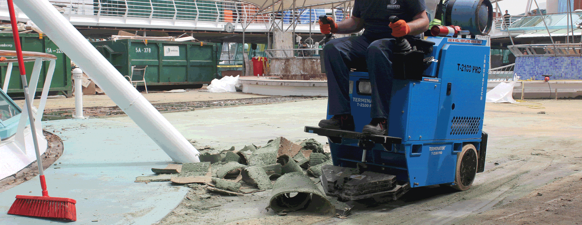 Worker operating a blue concrete cutter, breaking wet pavement at a construction site
