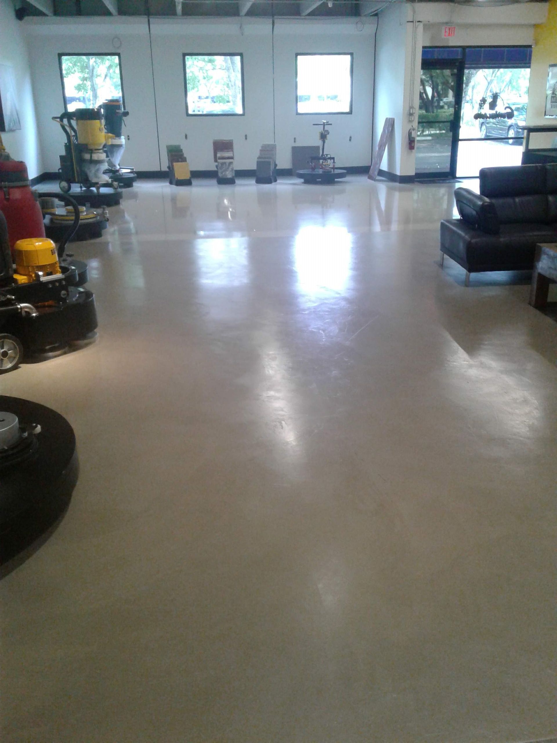 Empty showroom with polished floor, chairs, and seating area by large windows.