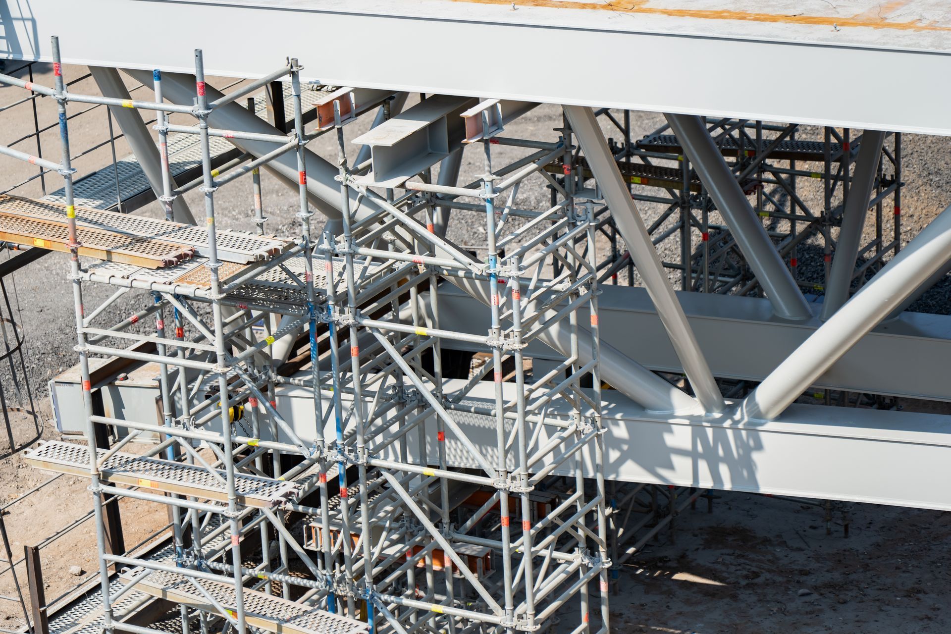 Scaffolding surrounds large steel beams at a construction site.