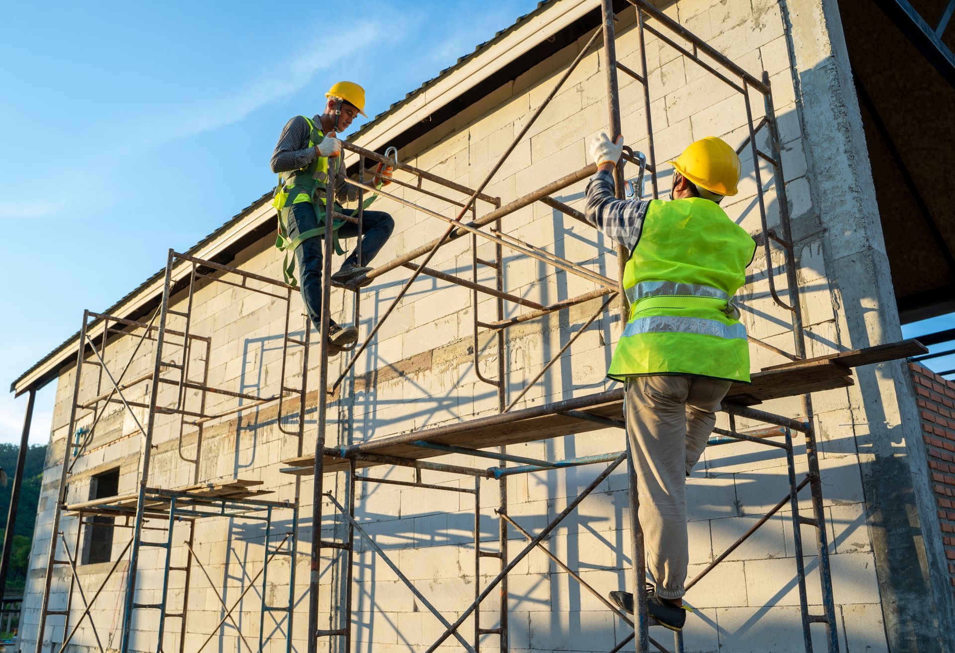 Two construction workers on metal scaffolding installing exterior walls. Two construction workers on metal scaffolding installing exterior walls.