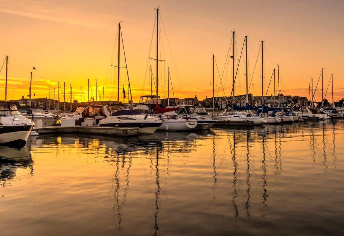 Sunset marina with docked sailboats and golden reflections on calm water