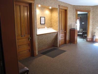 Hallway with three wooden doors, built-in shelf, and dark carpet.