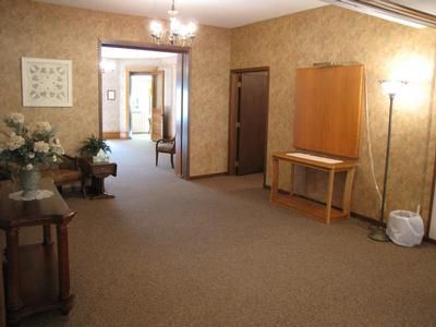 Interior of a room with brown carpet, walls, and furniture; a doorway leads to another room.