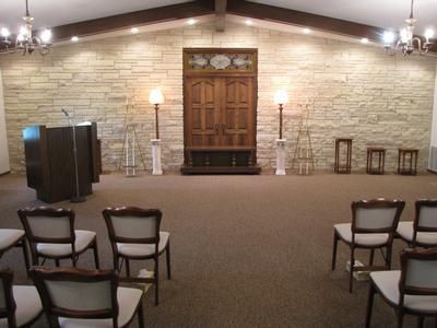 Interior of a sanctuary with chairs, a lectern, and a large wooden door.